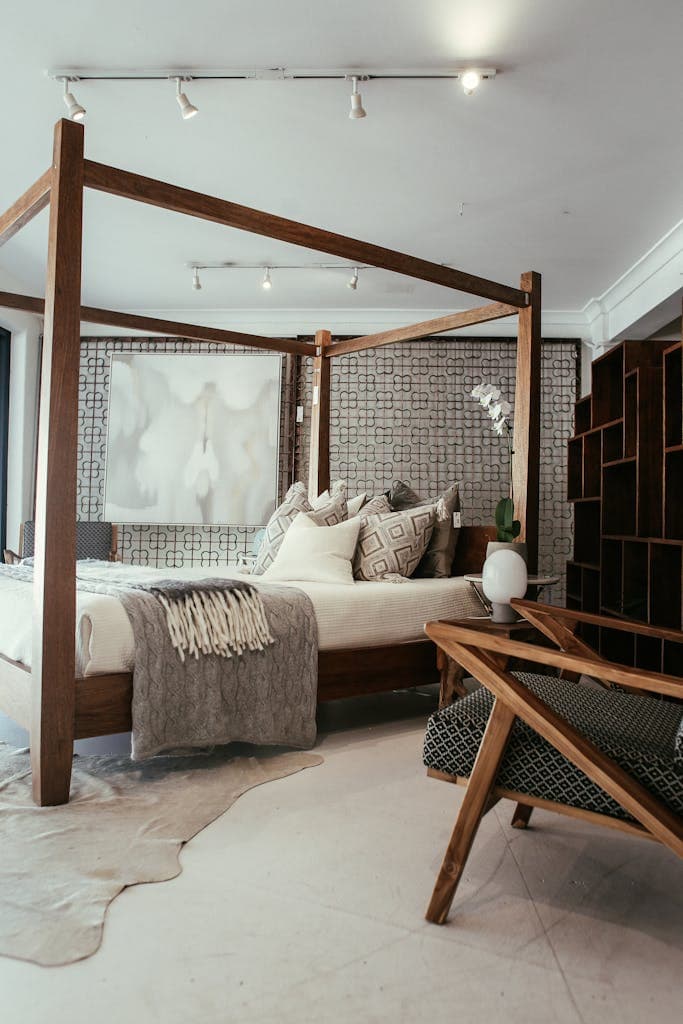 Elegant bedroom with a wooden canopy bed, armchair, and textured decor.